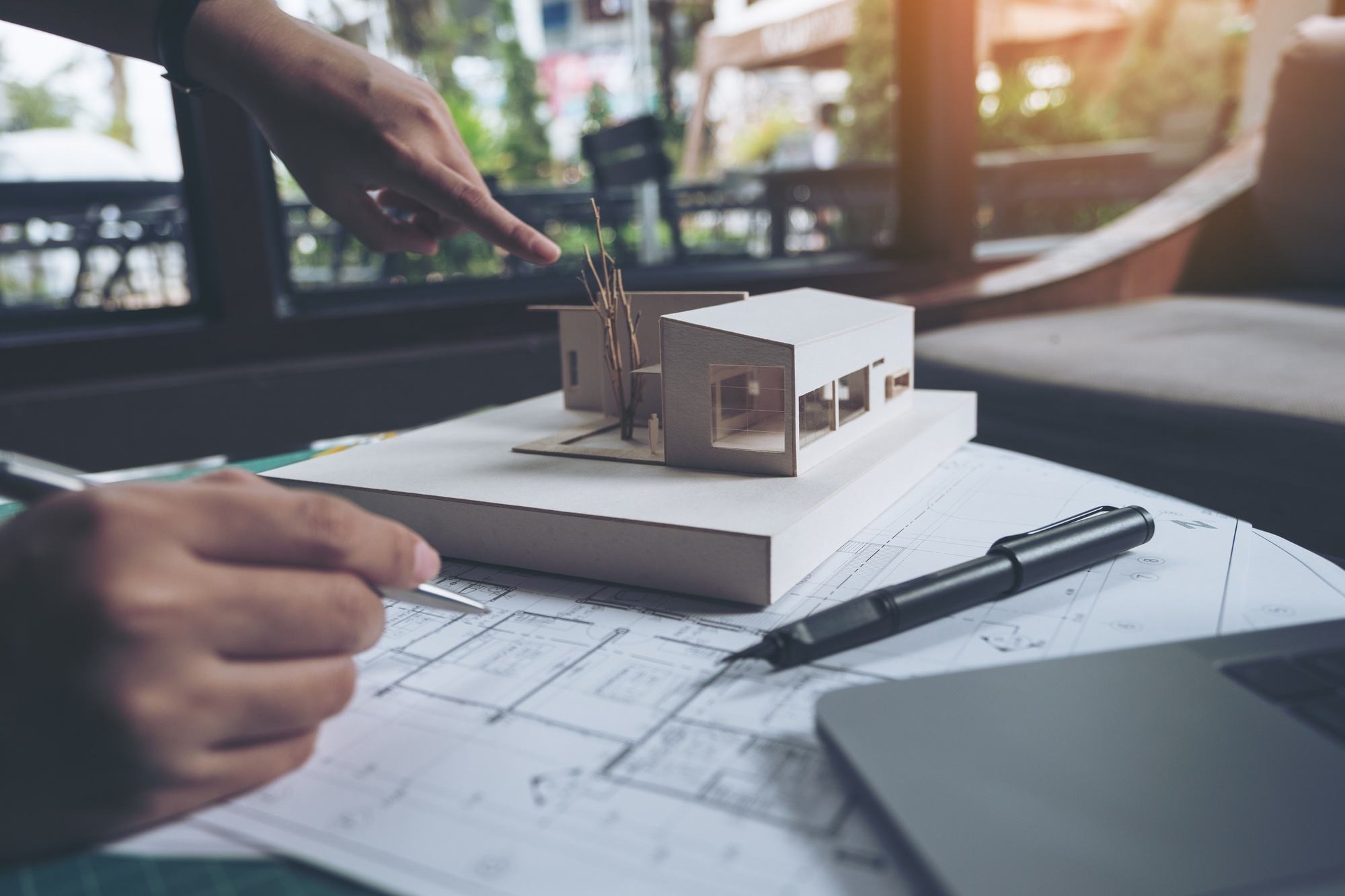 Architecte qui travaille sur un plan et une maquette en bois