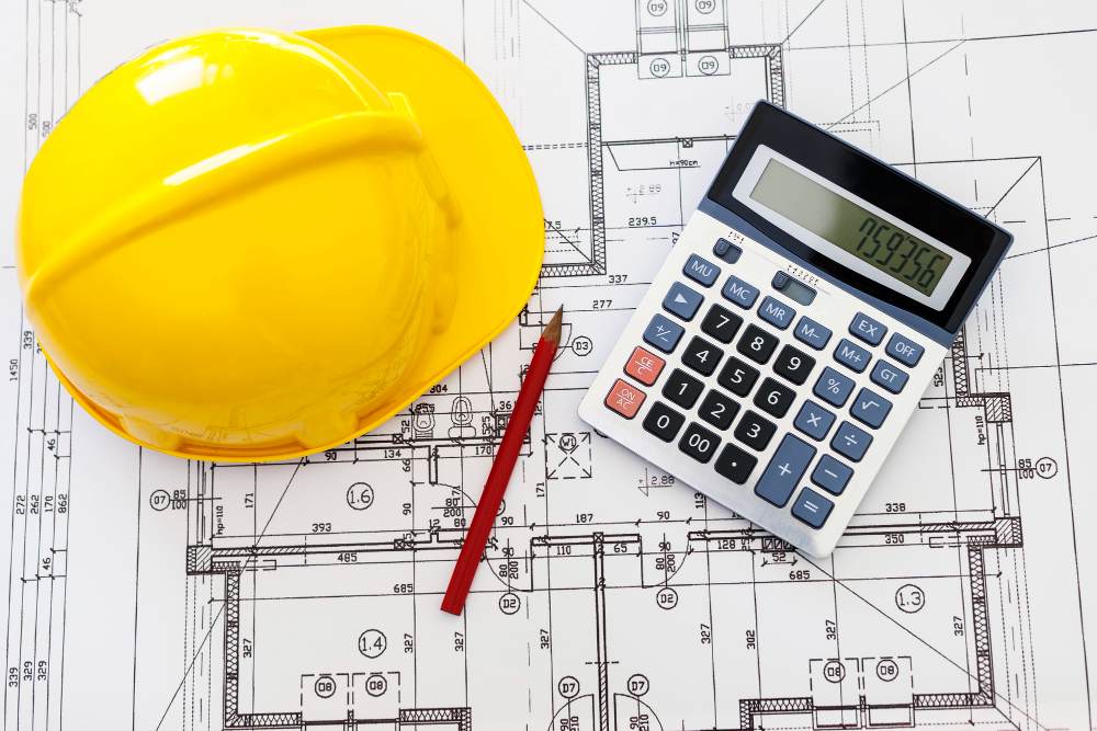casque sur une table avec plan de construction et calculatrice